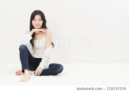 一位年輕女子穿著緊身牛仔褲、牛仔褲和牛仔褲，盤腿而坐 119135539