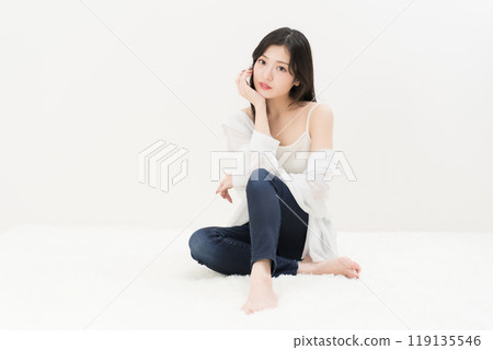 A young woman sitting cross-legged in skinny jeans, denim pants 119135546
