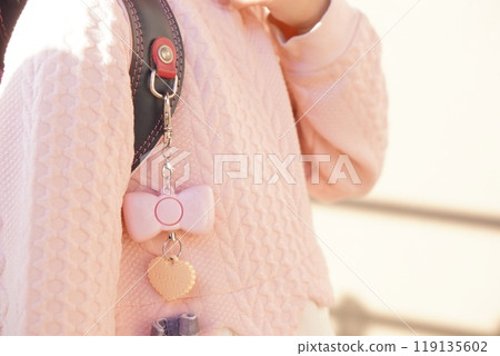 A cute, girly security alarm with a ribbon motif attached to a first grade elementary school student's school bag. A cute, girly security alarm with a ribbon motif attached to a first grade elementary school student's school bag. 119135602