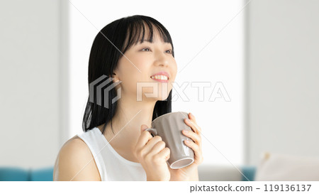 一個年輕女子從杯子裡喝飲料的美麗形象 一個年輕女子從杯子裡喝飲料的美麗形象 119136137
