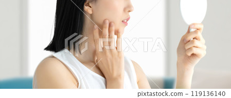 Young woman checking her skin in the mirror, beauty image 119136140
