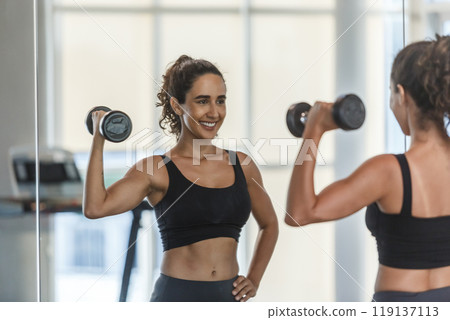 Healthy strong latina female holding dumbbells lifts weights exercise 119137113