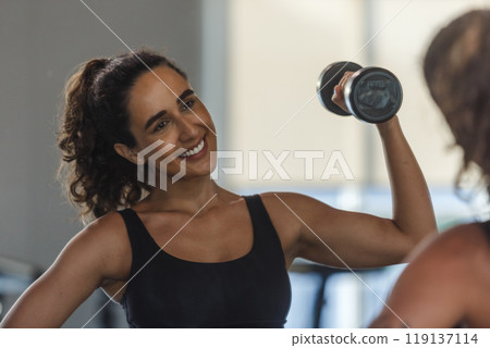 Healthy strong latina female holding dumbbells lifts weights exercise Healthy strong latina female holding dumbbells lifts weights exercise 119137114