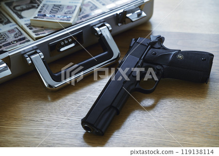 A gun and a stack of bills in an attaché case 119138114