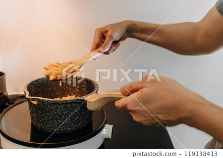 Man cooking homemade pasta in his small apartment kitchen. 119138413