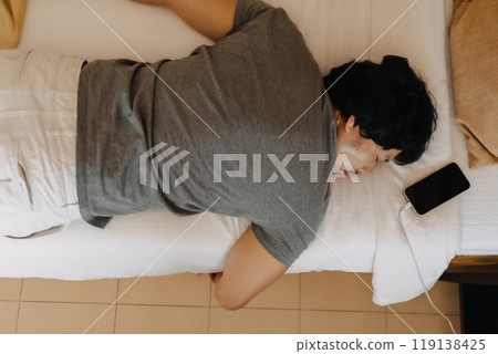 Close up face of sleepy man slept with his mobile phone left near his head. Close up face of sleepy man slept with his mobile phone left near his head. 119138425