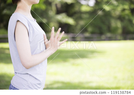 A young woman praying outdoors - Outdoor yoga image 119138784