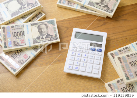 A stack of bills and a calculator on a desk (new bill version) A stack of bills and a calculator on a desk (new bill version) 119139839