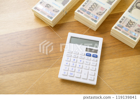 A stack of bills and a calculator on a desk (new bill version) 119139841