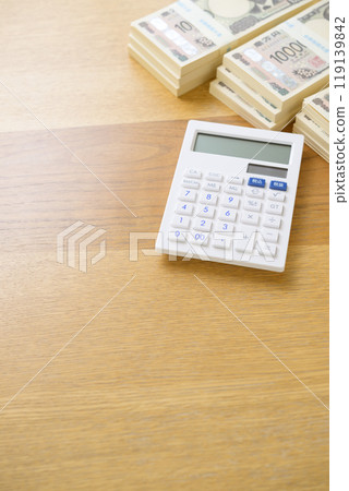 A stack of bills and a calculator on a desk (new bill version) 119139842