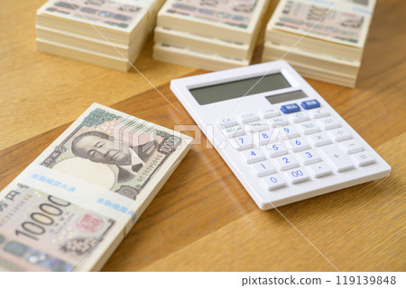A stack of bills and a calculator on a desk (new bill version) 119139848