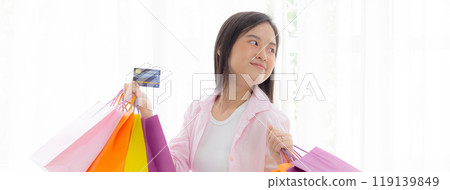 Young asian woman standing holding credit card and paper bag with satisfied. 119139849