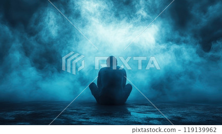 Solitary figure sitting in a dark misty environment surrounded by a moody atmospheric sky 119139962