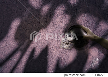 Witch hand with long black nail holding human head skull with grungy wall background, gives the image a spooky and scary mood. Evil, satan, zombie or monster hand 119140278