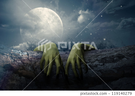 Two witch hands reaching out from a wooden log with full moon background. Scene is scary and creepy. The hand appearing to be a evil, satan, zombie or a monster hand 119140279