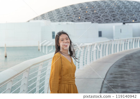 Asian woman standing in front of Louvre Abu Dhabi 119140942