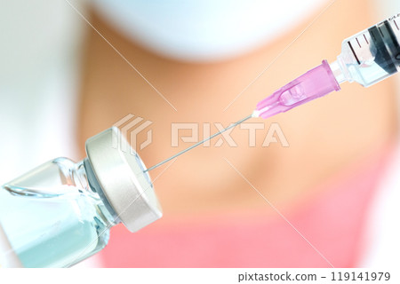 Doctor's hand holds a syringe and a blue vaccine covid19 bottle at the hospital. Health and medical concepts Doctor's hand holds a syringe and a blue vaccine covid19 bottle at the hospital. Health and medical concepts 119141979