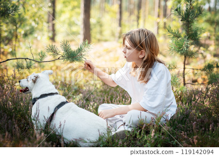 A child relaxing with a dog in a serene forest, surrounded by greenery and blooming flowers A child relaxing with a dog in a serene forest, surrounded by greenery and blooming flowers 119142094