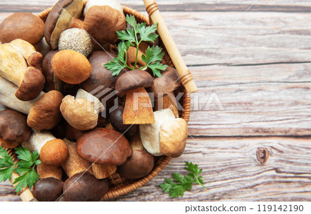 A vibrant assortment of fresh mushrooms and herbs in a woven basket on a rustic wooden table A vibrant assortment of fresh mushrooms and herbs in a woven basket on a rustic wooden table 119142190