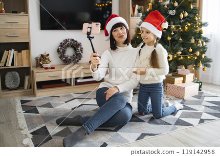 Mother and daughter taking selfie near Christmas tree Mother and daughter taking selfie near Christmas tree 119142958