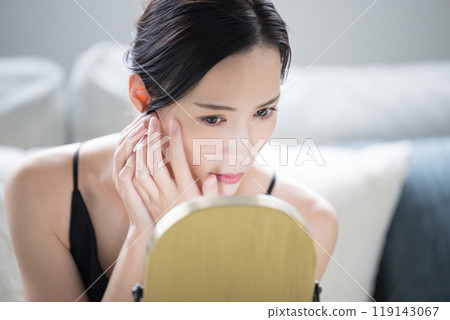 Close-up of a woman looking in the mirror and worrying about her skin condition 119143067