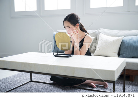 Wide angle of concerned woman looking in mirror and worrying about her skin condition Wide angle of concerned woman looking in mirror and worrying about her skin condition 119143071
