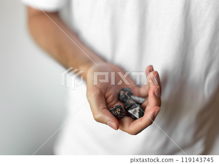 Hand holding dice for tabletop gaming enthusiasts and casual gamers 119143745