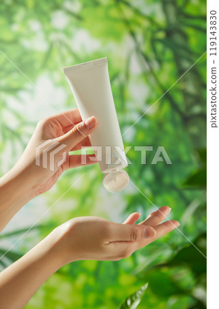 A template image for an ad features a lush bamboo forest backdrop with a model hand holding a white tube without a label and squeezing a cream sample into the other hand to show off a creamy texture. A template image for an ad features a lush bamboo forest backdrop with a model hand holding a white tube without a label and squeezing a cream sample into the other hand to show off a creamy texture. 119143830