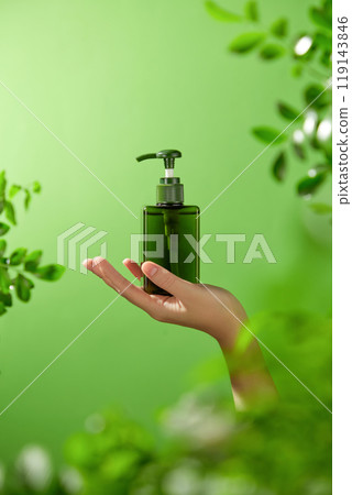 Natural product advertising image template showcases a mockup of a dark green pump bottle placed on the model's palm reaching out to the center of the image with a cool background of lush green trees. Natural product advertising image template showcases a mockup of a dark green pump bottle placed on the model's palm reaching out to the center of the image with a cool background of lush green trees. 119143846