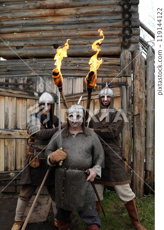 Holding Flaming Torches During Historical Reenactment at Wooden Structure 119144122