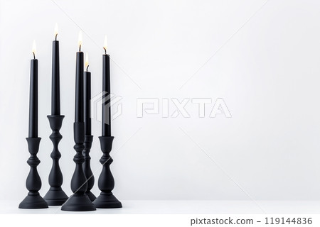 Black candles in stylish holders on a plain white background. Minimalistic display for home Halloween decor concepts Black candles in stylish holders on a plain white background. Minimalistic display for home Halloween decor concepts 119144836