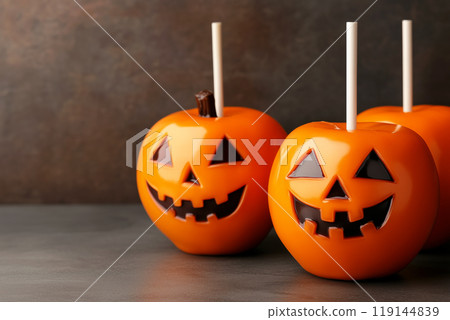 Halloween themed candy apples with jack-o'-lantern faces on festive background. Concept of Halloween treats 119144839