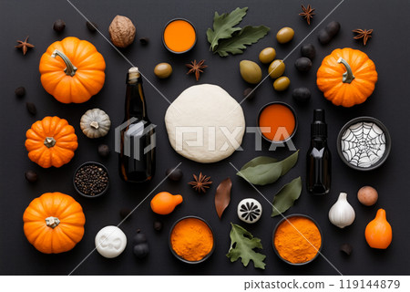 Halloween themed baking ingredients including pumpkins, spices, and dough with bat cutouts, arranged on dark background. 119144879