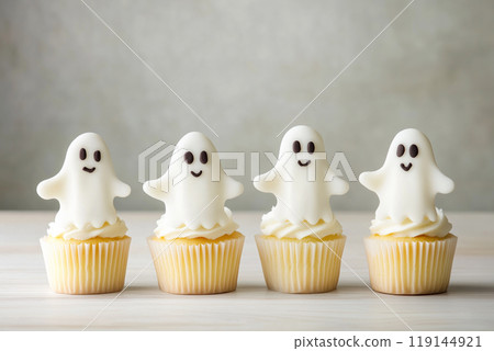 Halloween cupcakes topped with ghostly white frosting and orange wrappers on paper background. Autumn treat. 119144921