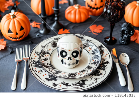 Halloween themed table setting with skulls, black pumpkins, and ornate cutlery. Concept of spooky dining decor 119145035