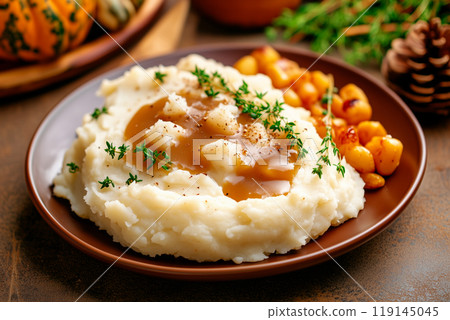 Plate of creamy mashed potatoes topped with rich gravy and herbs on a rustic wooden table. Concept for Thanksgiving day 119145045