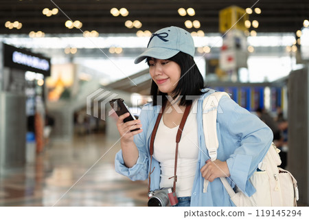Young woman using mobile phone in an airport terminal for checking flight information 119145294