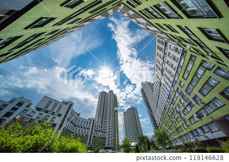 Green facade apartment buildings framing sunny blue sky with clouds Green facade apartment buildings framing sunny blue sky with clouds 119146628