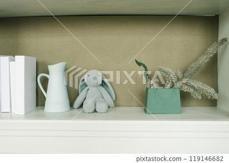 White shelf with a rabbit stuffed animal and a green vase 119146682