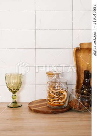 Green glass with a stem and a wooden tray with a jar of orange slices and a bottle of beer Green glass with a stem and a wooden tray with a jar of orange slices and a bottle of beer 119146688