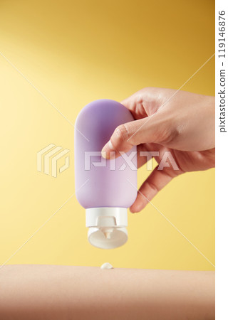 A model hand holds an unlabeled purple lotion bottle against a bright yellow background like a sun, emphasizing the uniqueness of the product, perfect for the advertisement image template. 119146876