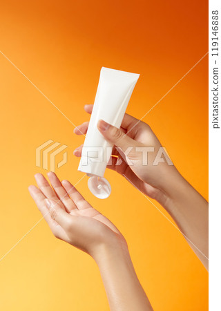 Image templates for skincare ads show a white, label-free tube that is grasped firmly in the hand and is unbranded. The orange backdrop creates a striking contrast, signifying brightness and energy. Image templates for skincare ads show a white, label-free tube that is grasped firmly in the hand and is unbranded. The orange backdrop creates a striking contrast, signifying brightness and energy. 119146888