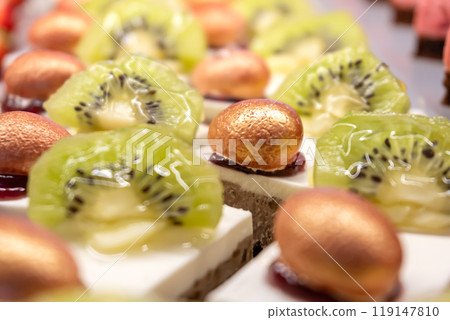 Cakes decorated with kiwi slices and nuts in sugar glaze. Sweet dessert. Close-up. Cakes decorated with kiwi slices and nuts in sugar glaze. Sweet dessert. Close-up. 119147810