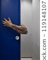 An intriguing arm emerges from a blue door in a contemporary space, captivating viewers 119148107