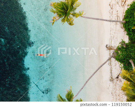 Woman floating and relaxing in tropical ocean on her vacations. Aerial view of woman with palm trees 119150052