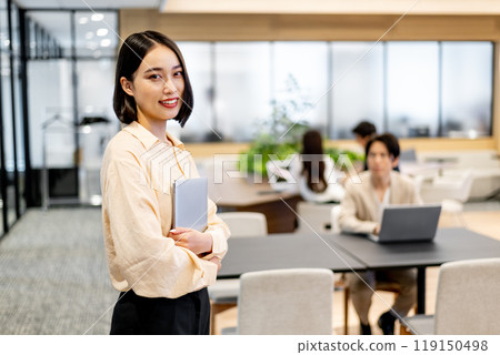 A business person holding a laptop computer and looking at it with a smile A business person holding a laptop computer and looking at it with a smile 119150498