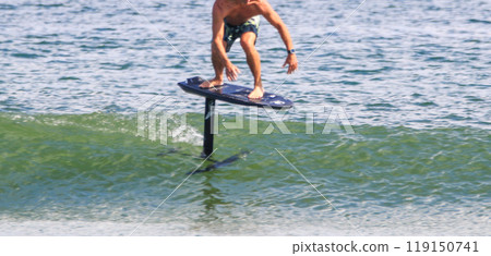 Side view of a shirtless man hydro foili surfing on top of a small wave close up 119150741