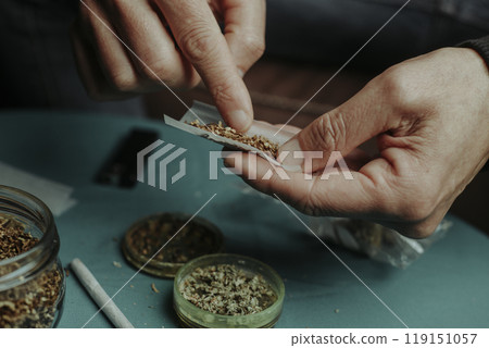 puts some tobacco on a rolling paper to make a joint 119151057