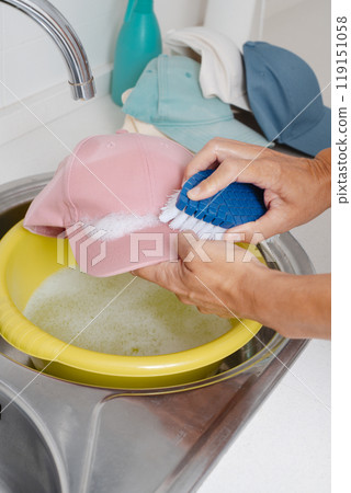man is washing a pink cap using a brush 119151058