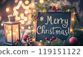 Festive chalkboard and Christmas decorations, lighting garland, candles, pine cone near Christmas tree. Text - Merry Christmas! Xmas card. 119151122